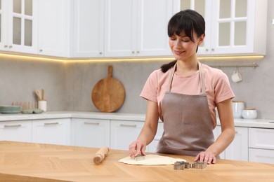 Photo of Woman cutting out cookies at wooden table indoors. Space for text