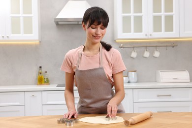 Photo of Woman cutting out cookies at wooden table indoors