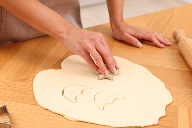 Photo of Woman cutting out cookies at wooden table indoors, closeup