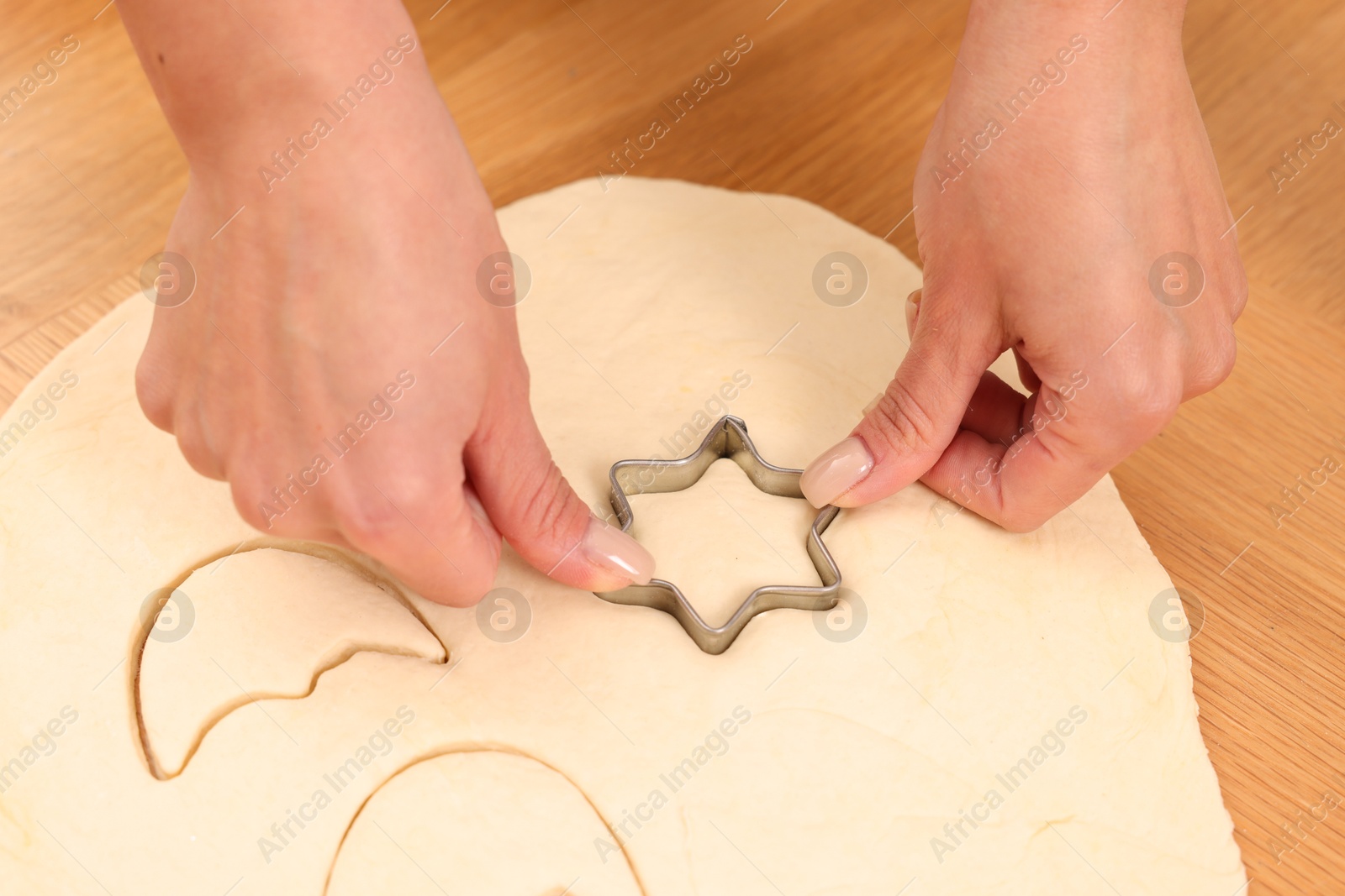 Photo of Woman cutting out cookies at wooden table indoors, closeup