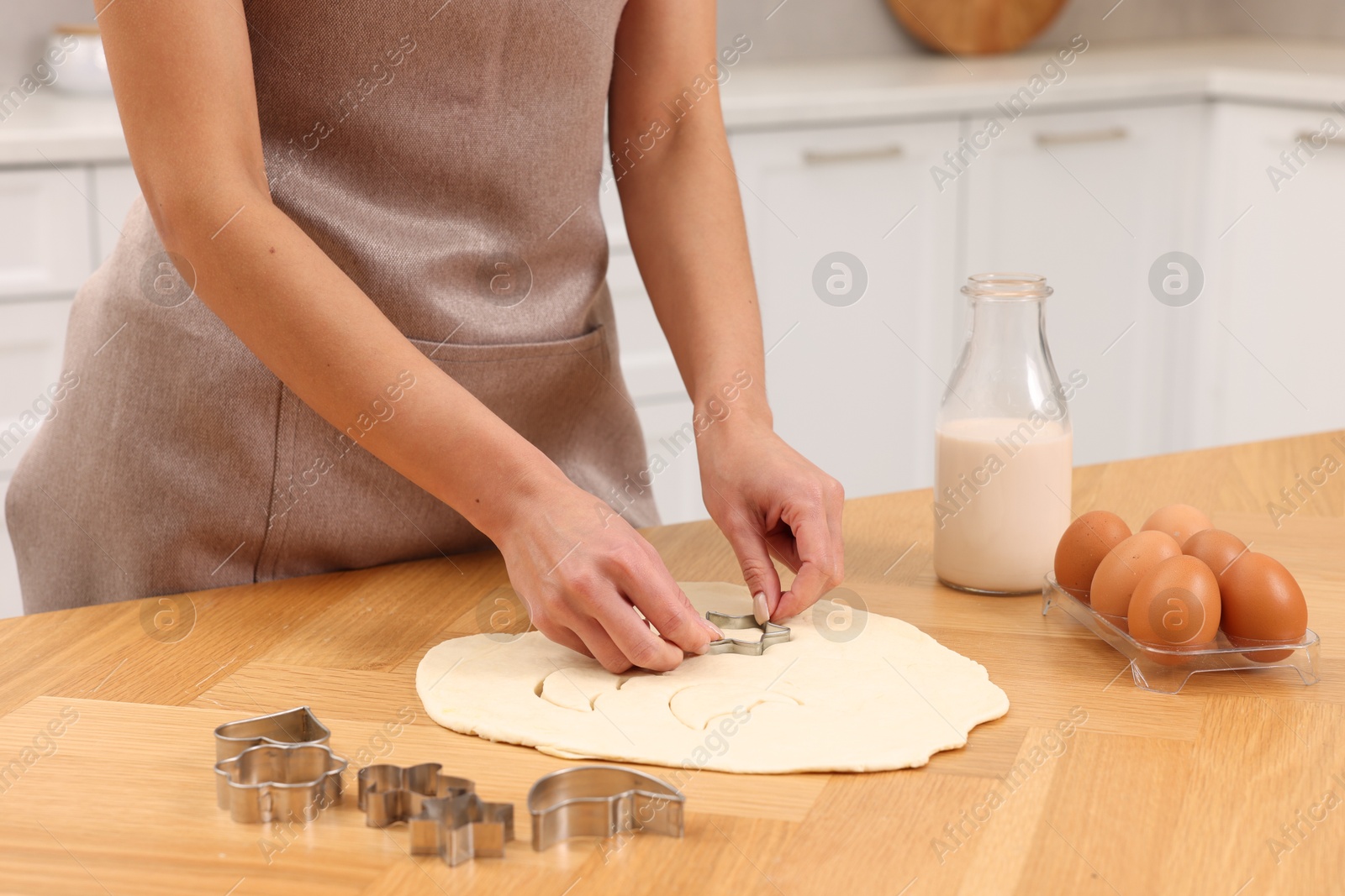 Photo of Woman cutting out cookies at wooden table indoors, closeup