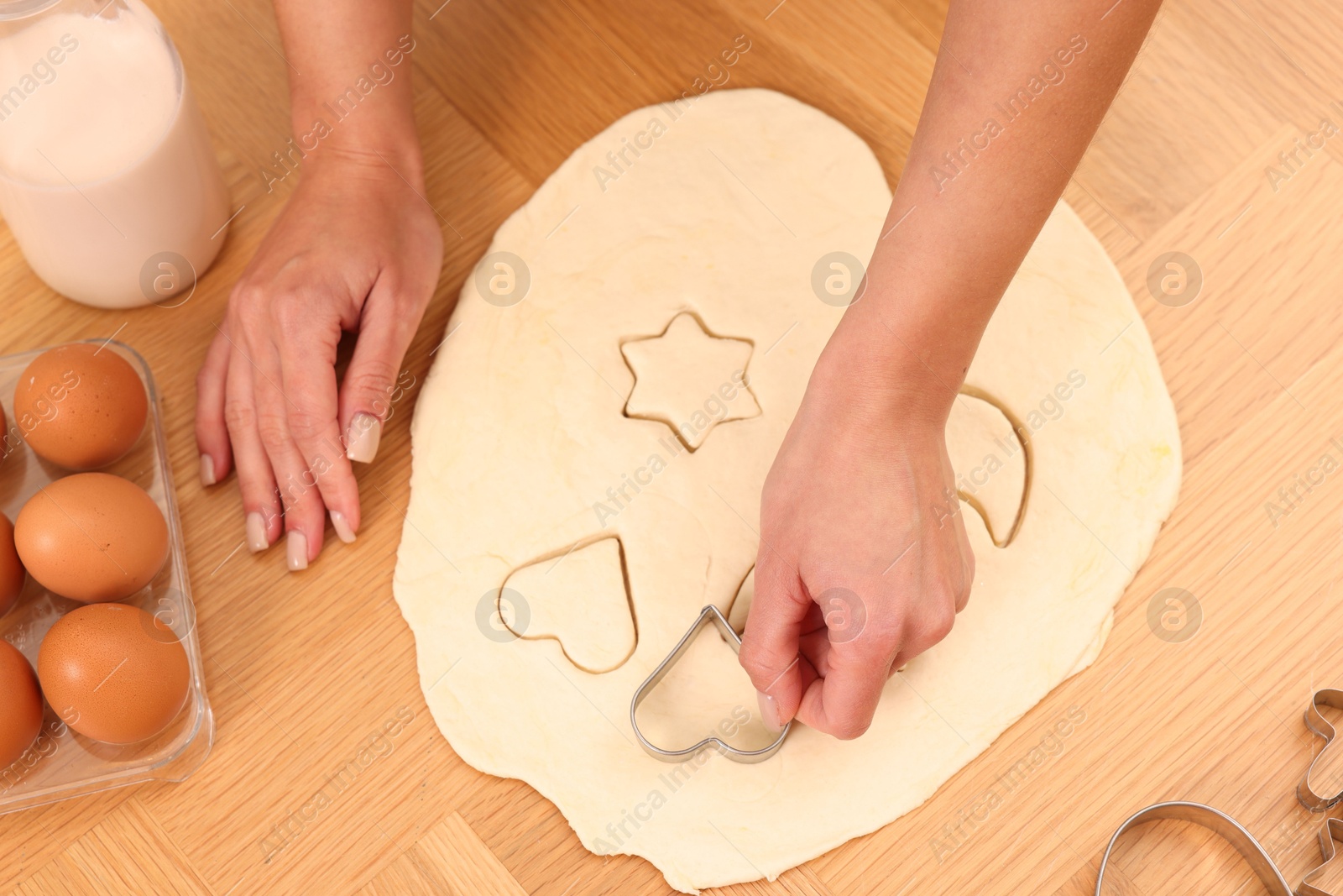 Photo of Woman cutting out cookies at wooden table indoors, top view