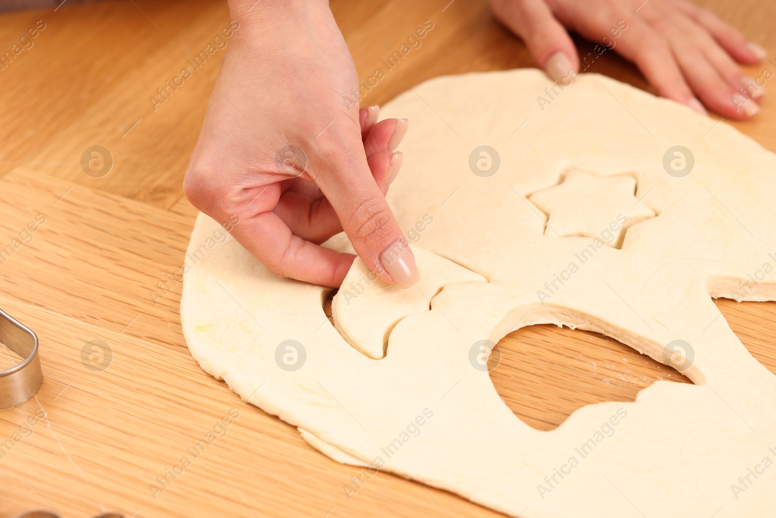 Photo of Woman with raw cookies at wooden table, closeup