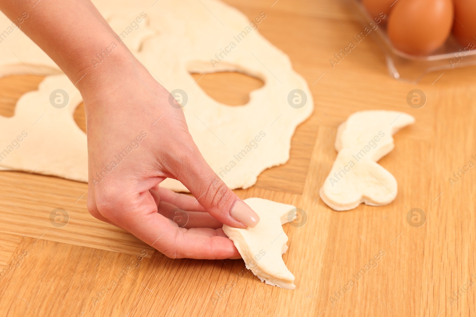 Photo of Woman with raw cookies at wooden table, closeup