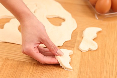 Woman with raw cookies at wooden table, closeup