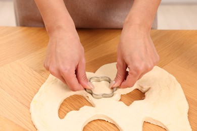 Photo of Woman cutting out cookies at wooden table indoors, closeup