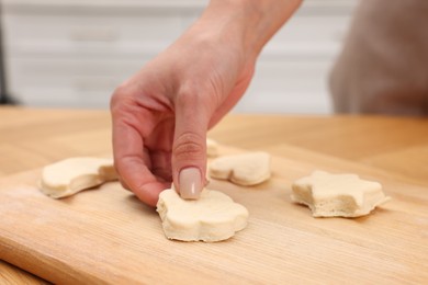 Photo of Woman with raw cookies at wooden table, closeup