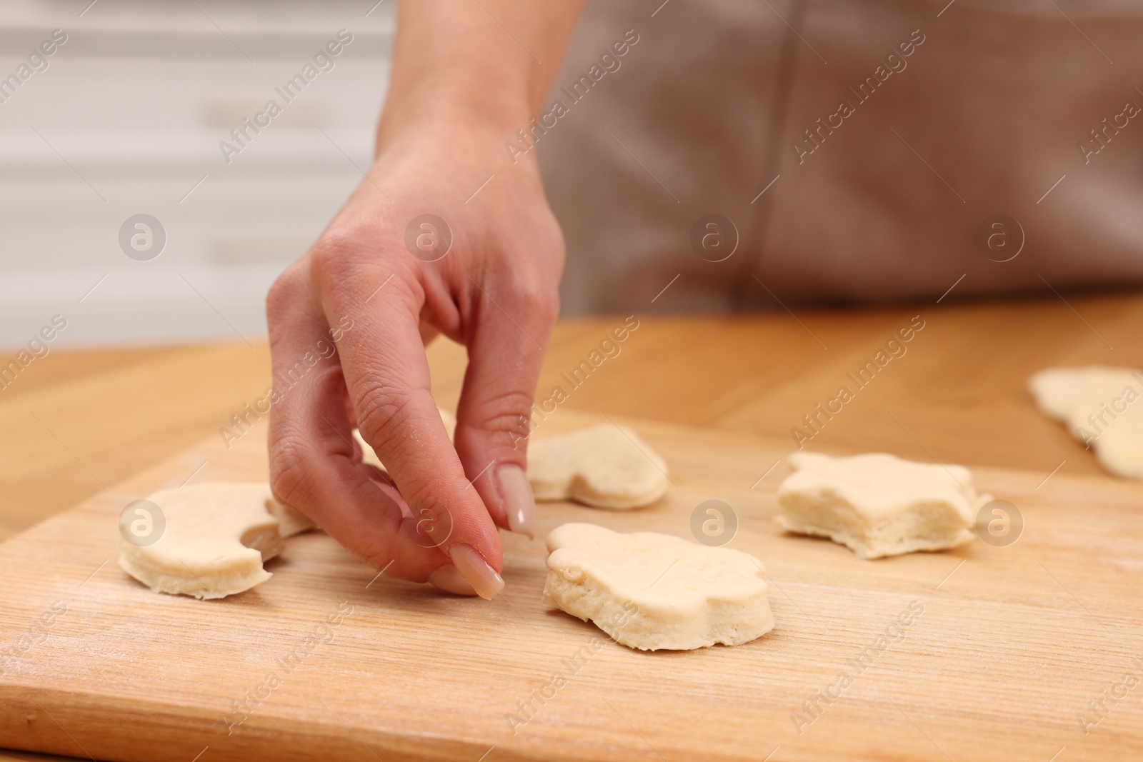 Photo of Woman with raw cookies at wooden table, closeup