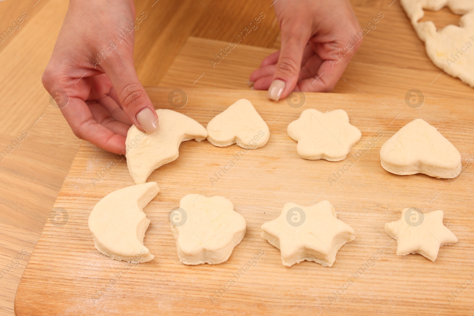 Photo of Woman with raw cookies at wooden table, closeup