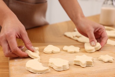 Photo of Woman with raw cookies at wooden table, closeup