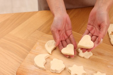 Photo of Woman with raw cookies at wooden table, closeup