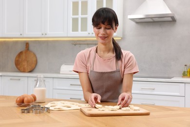 Photo of Woman with raw cookies at wooden table