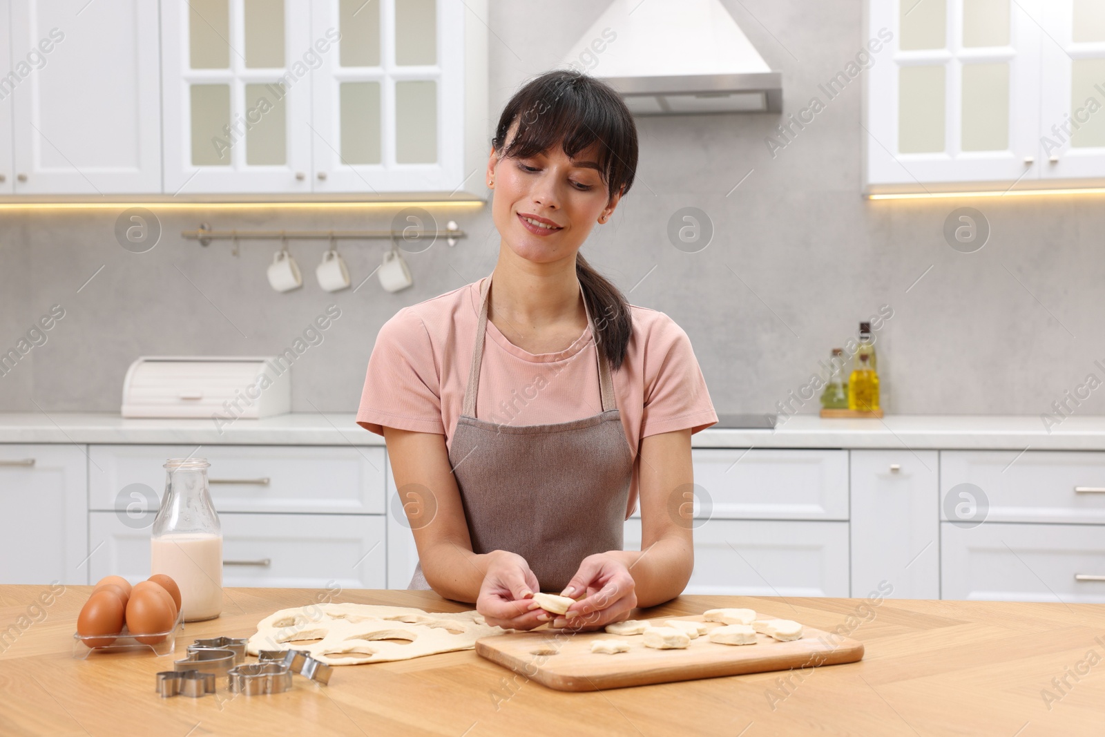 Photo of Woman with raw cookies at wooden table