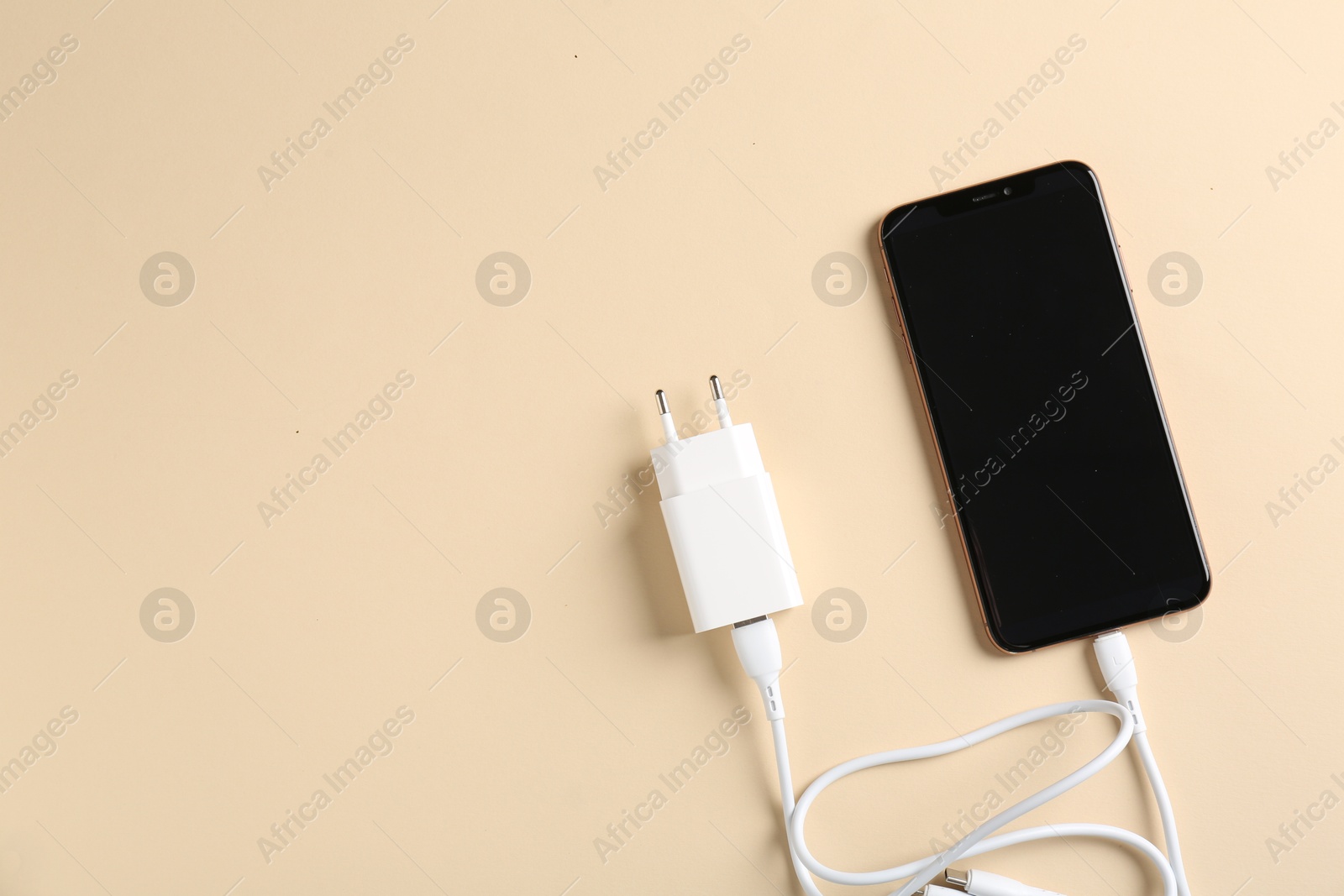 Photo of Triple charge cable connected to smartphone on beige background, top view. Space for text