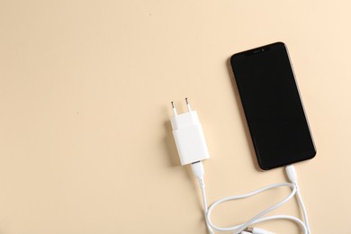 Photo of Triple charge cable connected to smartphone on beige background, top view. Space for text