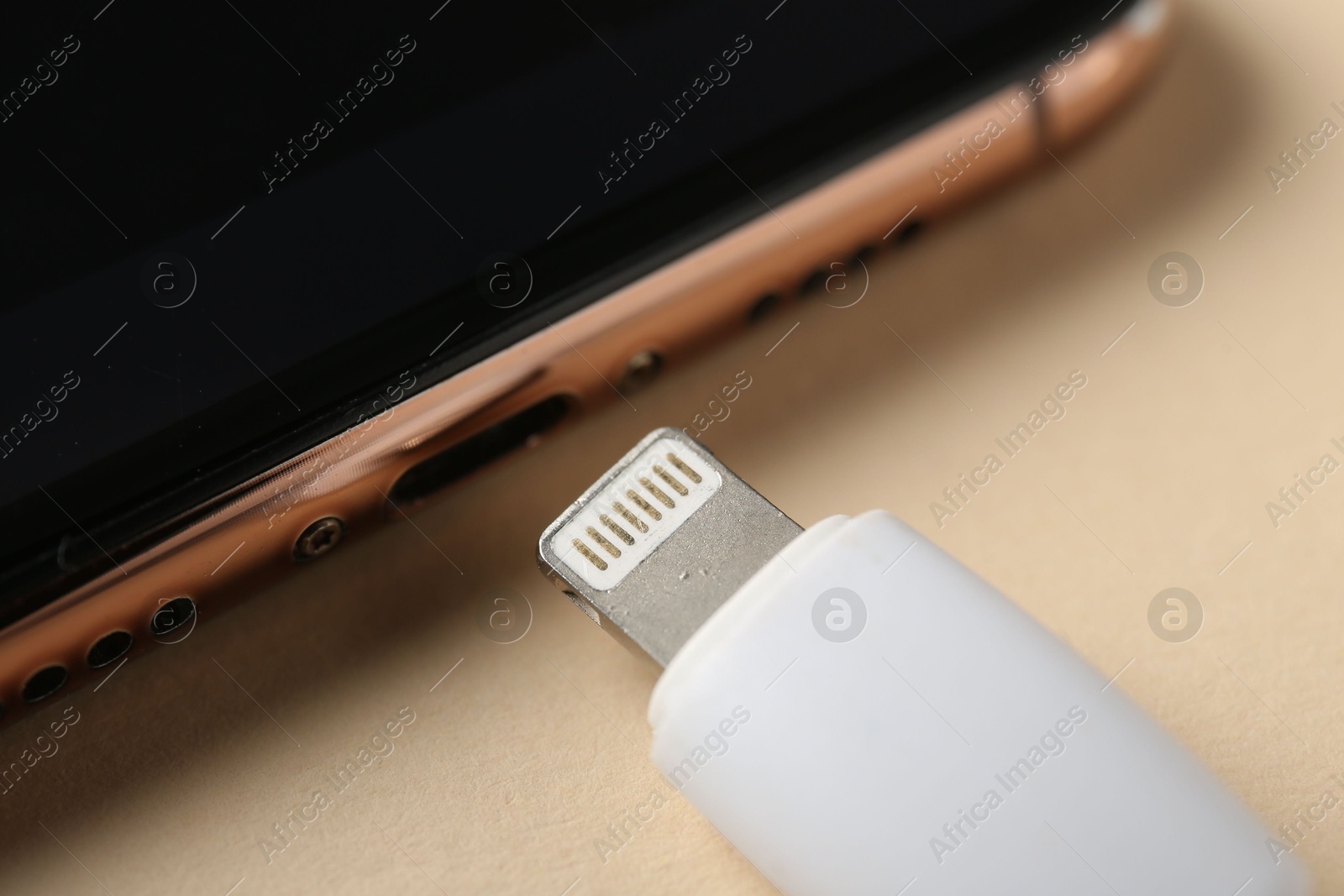 Photo of USB charge cable and smartphone on beige background, closeup