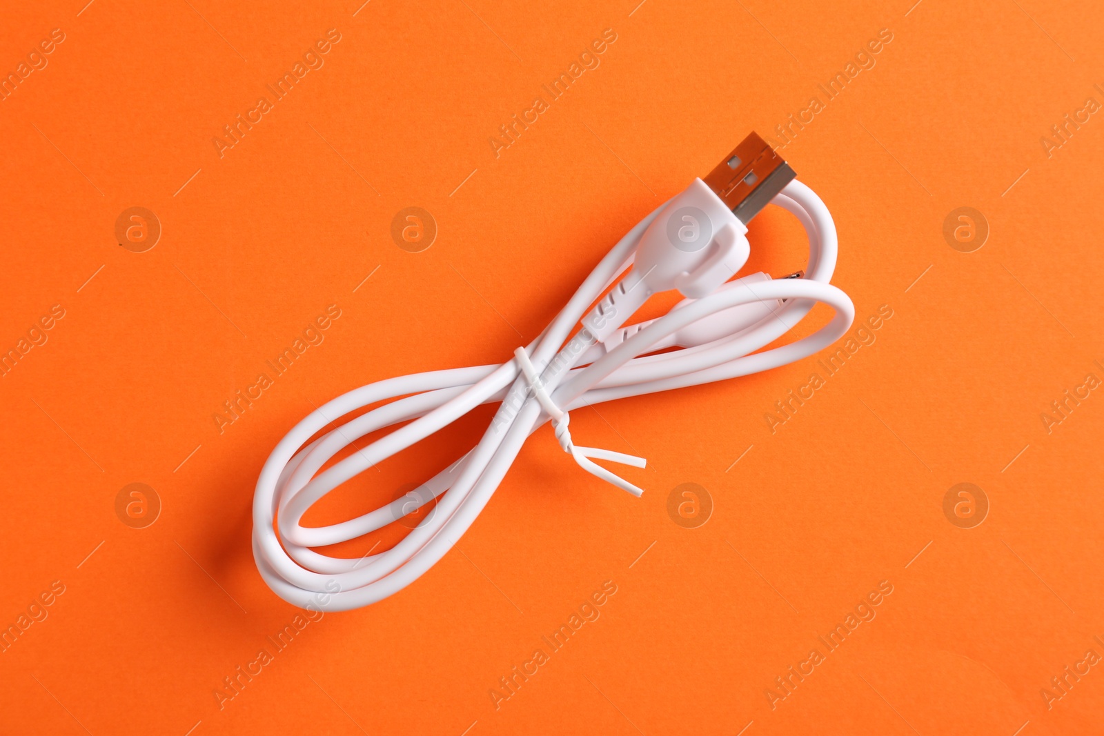 Photo of USB charge cable on orange background, top view