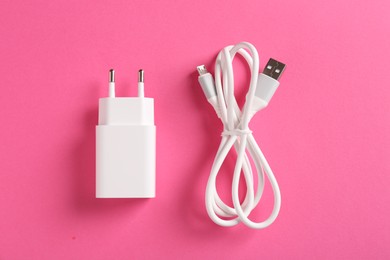 Photo of USB power adapter and charge cable on pink background, flat lay