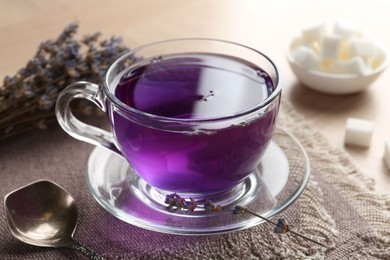 Aromatic lavender tea in glass cup and spoon on table, closeup