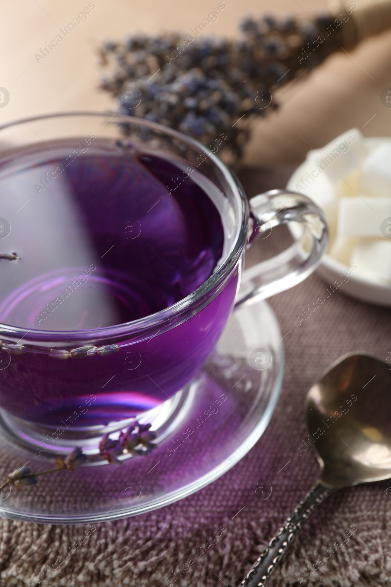 Photo of Aromatic lavender tea in glass cup and spoon on table, closeup