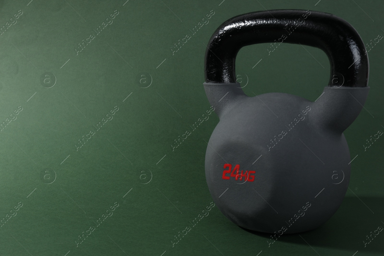 Photo of One kettlebell on dark green background. Space for text