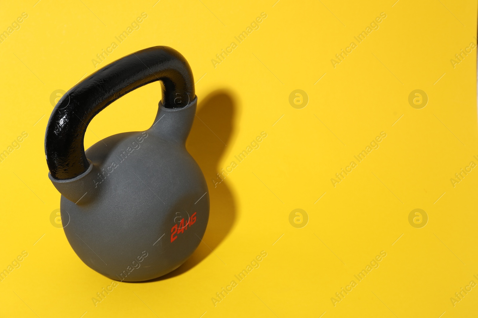 Photo of One kettlebell on yellow background. Space for text