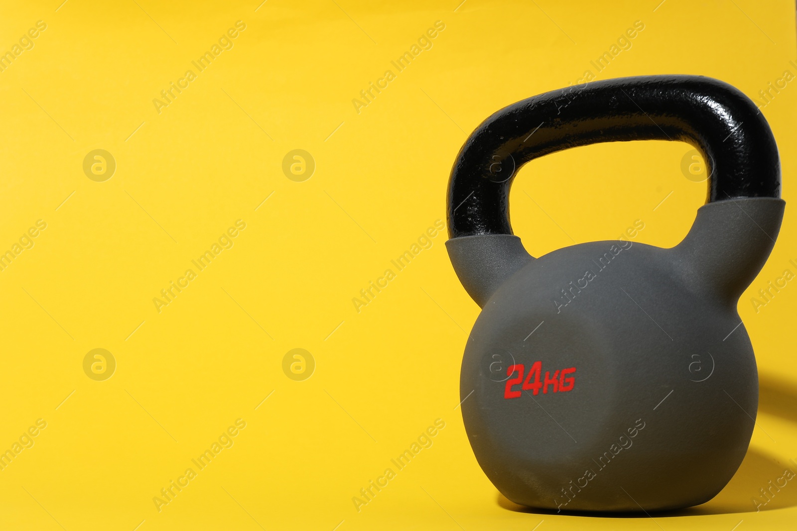 Photo of One kettlebell on yellow background. Space for text