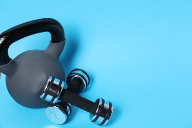 Photo of Kettlebell and dumbbells on light blue background. Space for text