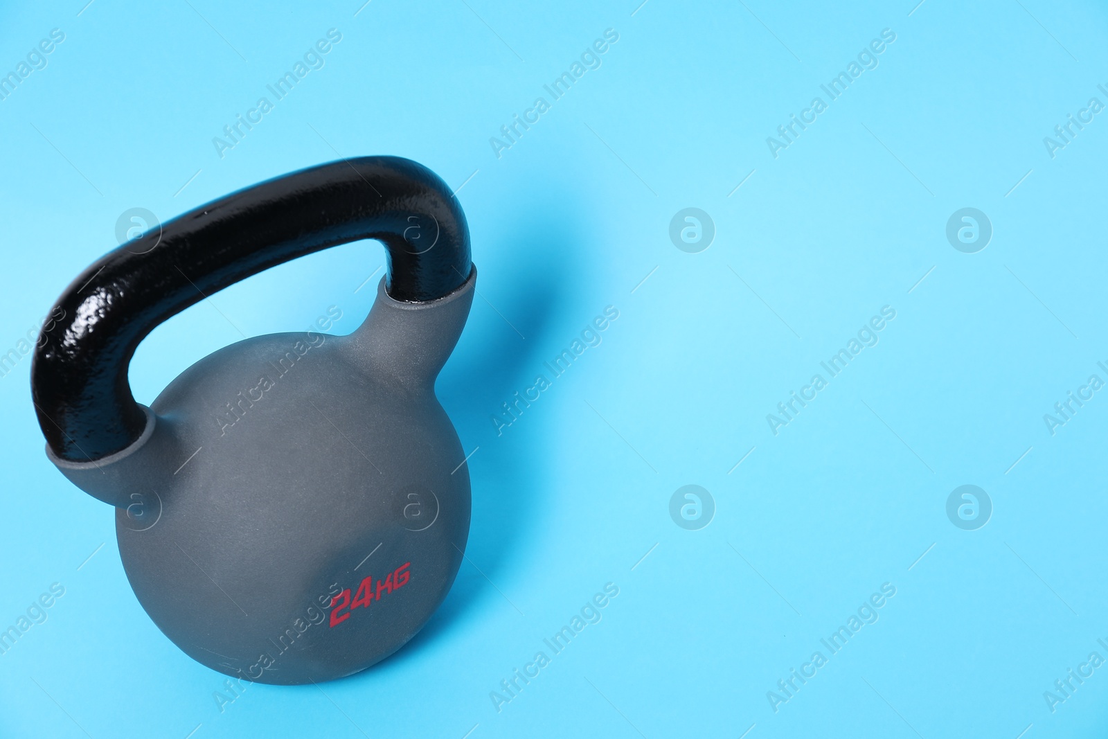 Photo of One kettlebell on light blue background. Space for text