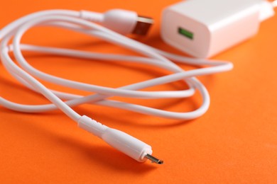 Photo of USB power adapter with charge cable on orange background, closeup