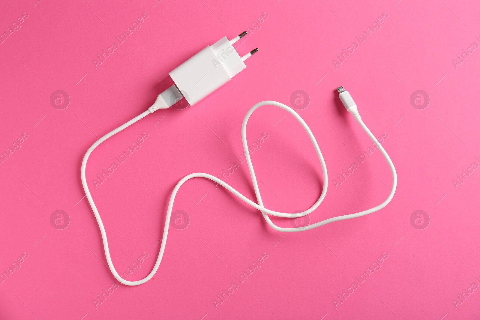 Photo of USB power adapter with charge cable on pink background, top view