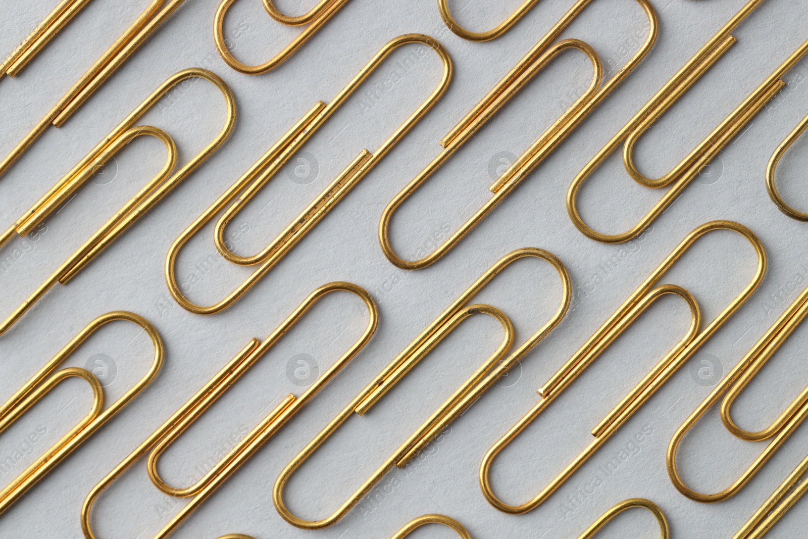 Photo of Golden paper clips on light background, flat lay