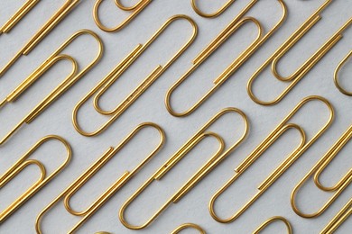 Photo of Golden paper clips on light background, flat lay