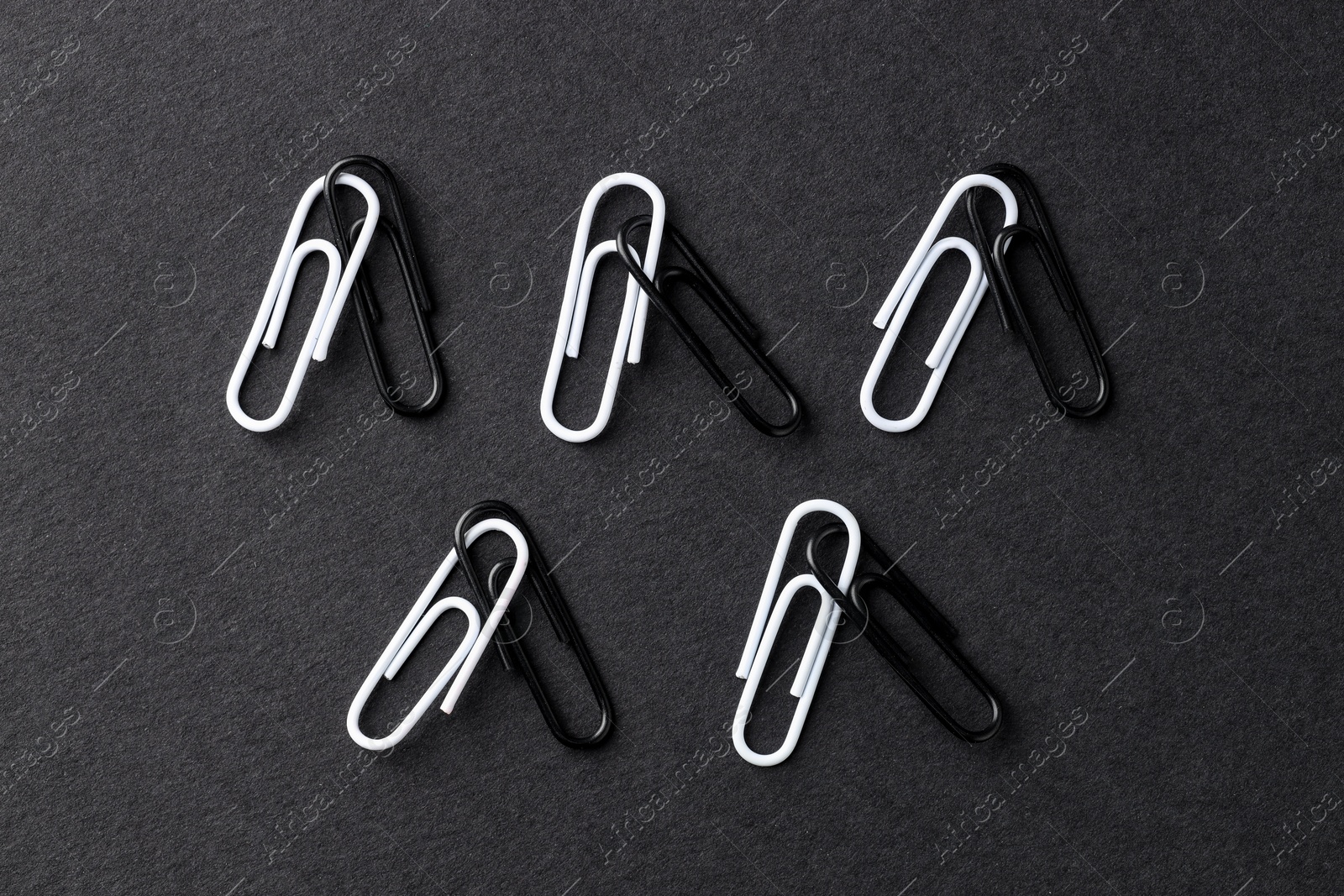 Photo of Many paper clips on black background, flat lay