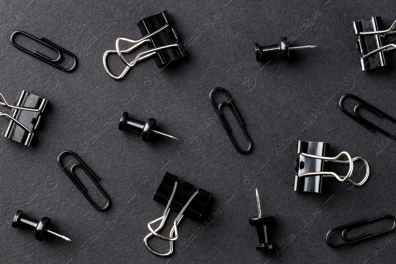 Photo of Paper clips and pins on black background, flat lay