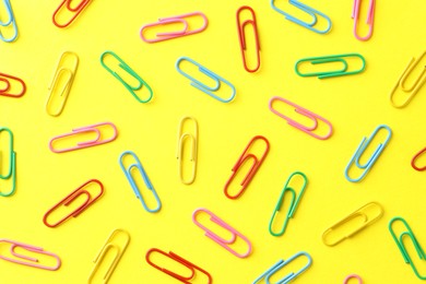 Photo of Colorful paper clips on yellow background, flat lay