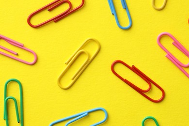 Photo of Colorful paper clips on yellow background, flat lay