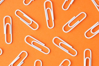 Photo of Many paper clips on orange background, flat lay