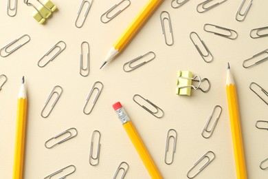 Photo of Paper clips and pencils on beige background, flat lay