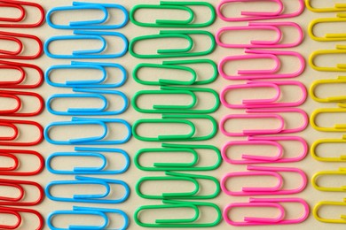 Photo of Colorful paper clips on beige background, flat lay