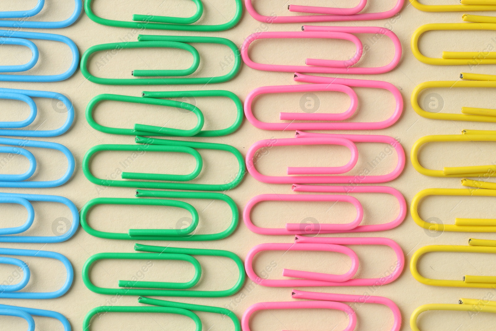 Photo of Colorful paper clips on beige background, flat lay