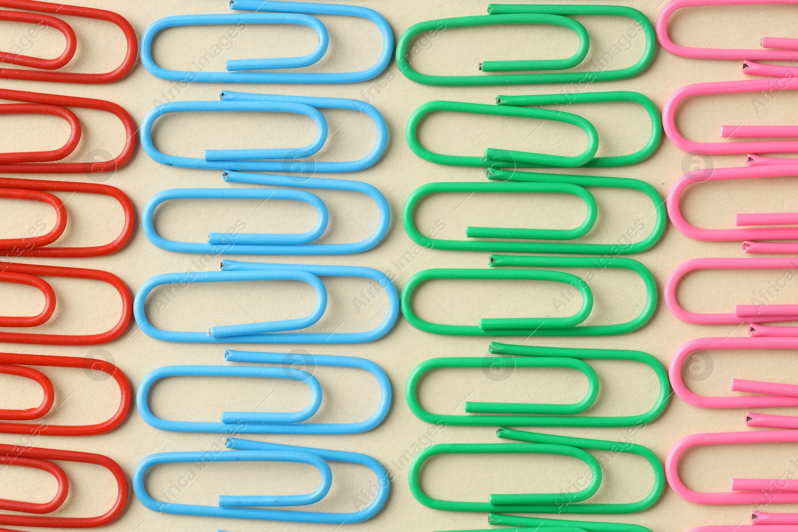 Photo of Colorful paper clips on beige background, flat lay