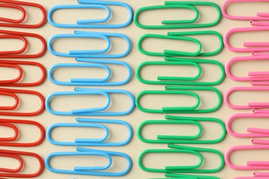 Photo of Colorful paper clips on beige background, flat lay