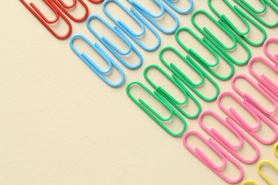 Photo of Colorful paper clips on beige background, flat lay. Space for text