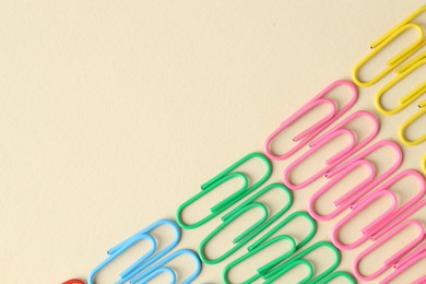 Photo of Colorful paper clips on beige background, flat lay. Space for text