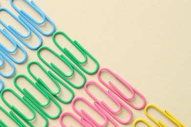 Photo of Colorful paper clips on beige background, flat lay. Space for text