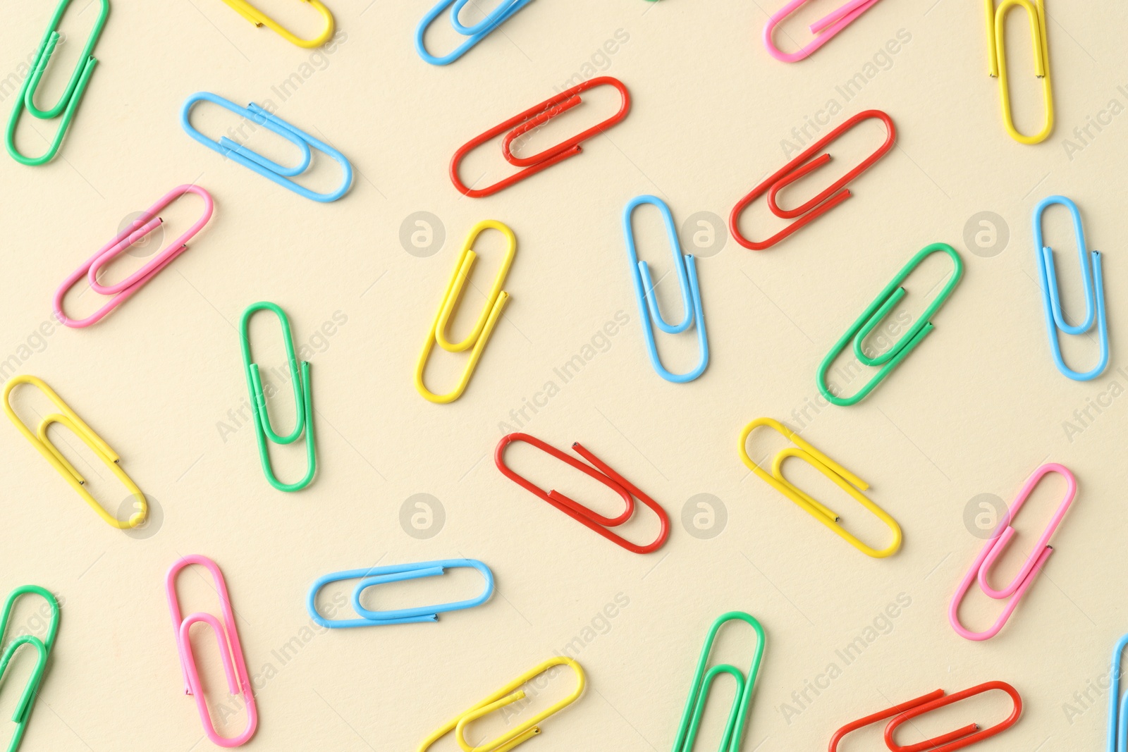 Photo of Colorful paper clips on beige background, flat lay