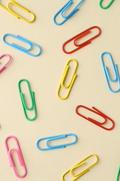 Colorful paper clips on beige background, flat lay