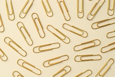 Photo of Golden paper clips on beige background, flat lay