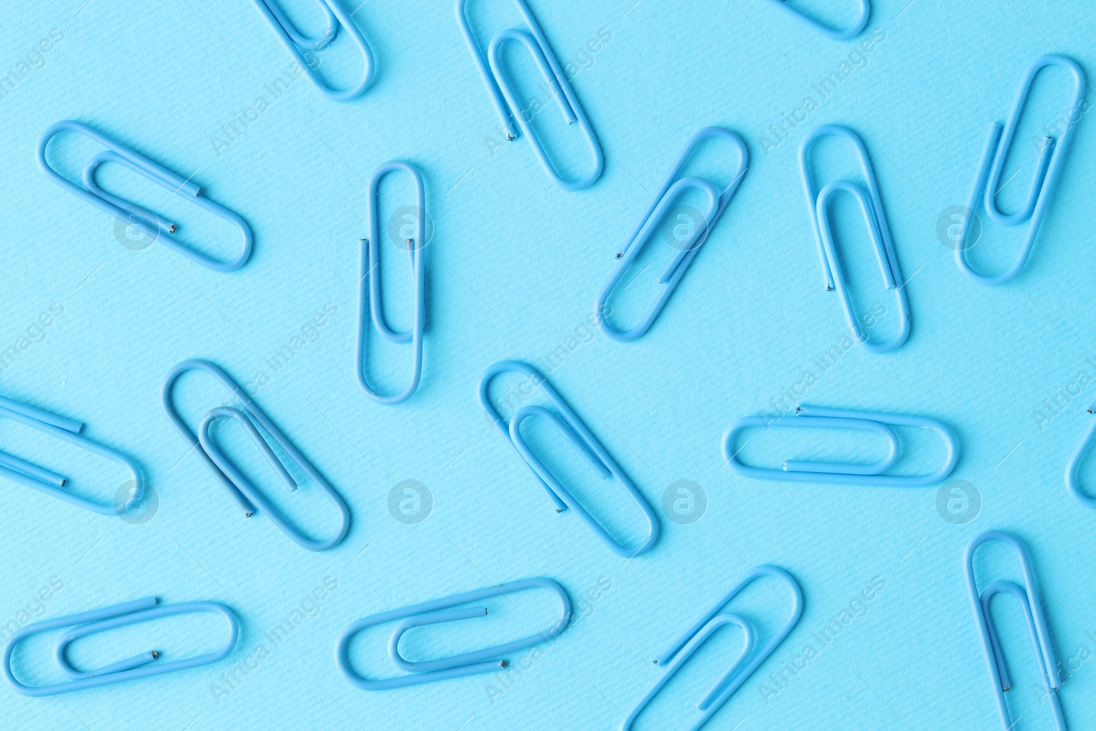 Photo of Many paper clips on light blue background, flat lay